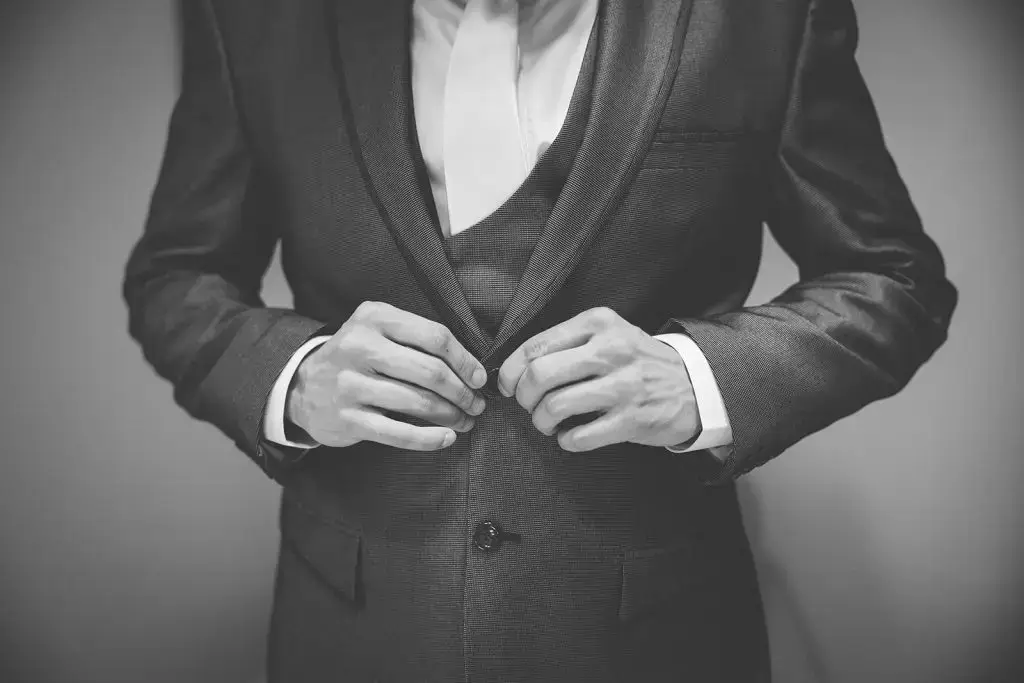 groom buttoning suit jacket
