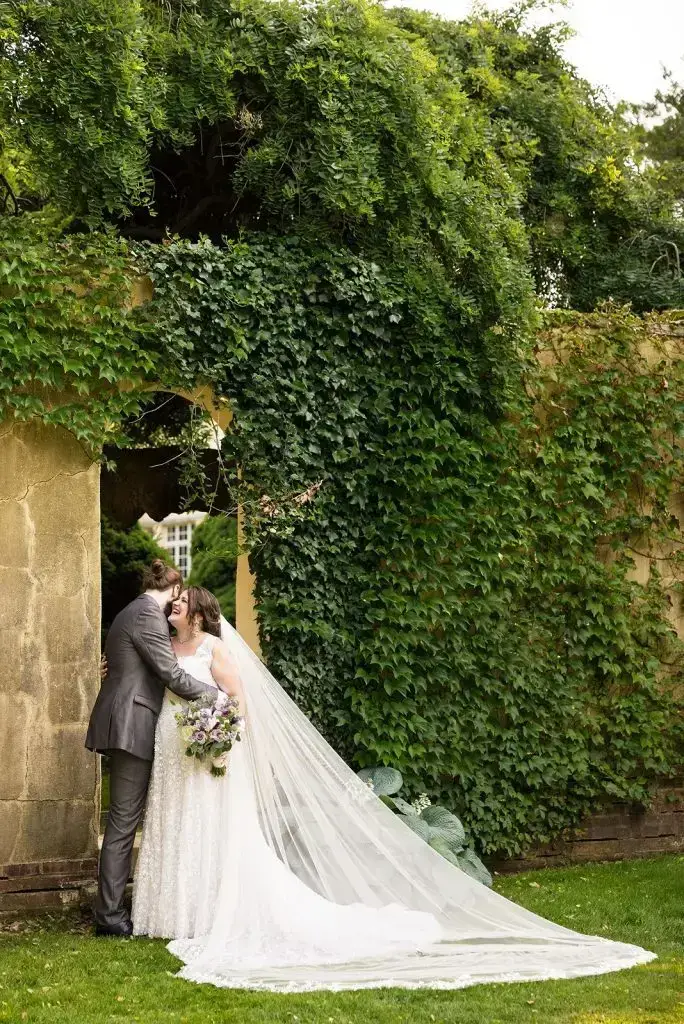couple against the ivy-covered wall at their Mansion at Oyster Bay wedding - from Leah E. Moss Designs